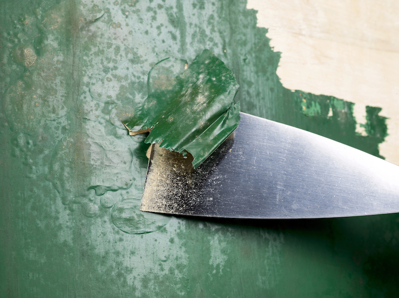 Paint being stripped from a wood surface